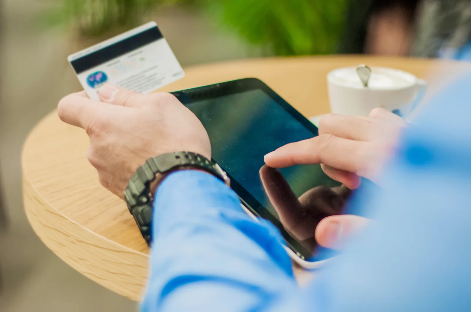 Kund som betalar med kort i en webbutik via surfplatta på ett café